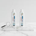 Two bottles of anti-slip gel on marble surface with gel drops and magnifying glass